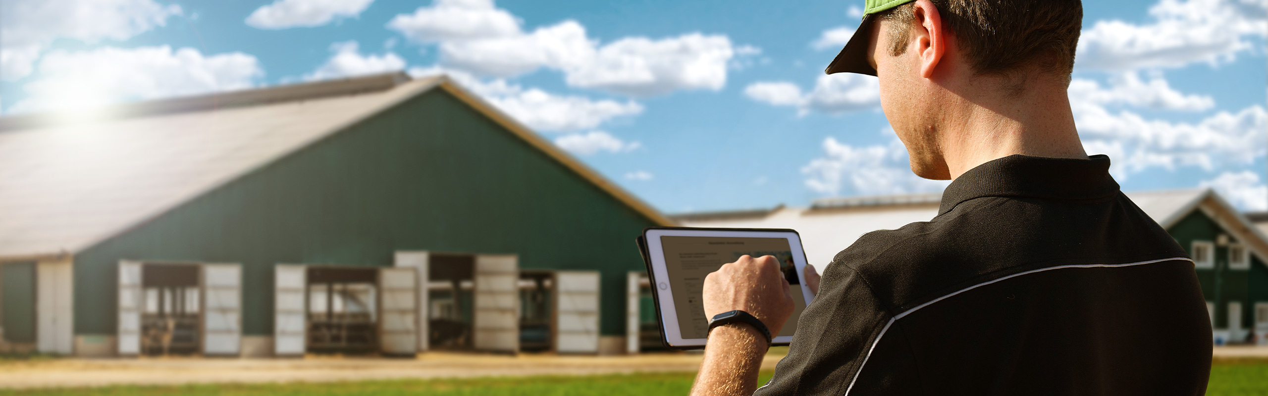 En landmand med en tablet står foran sin gård og tilmelder sig nyhedsbrevet