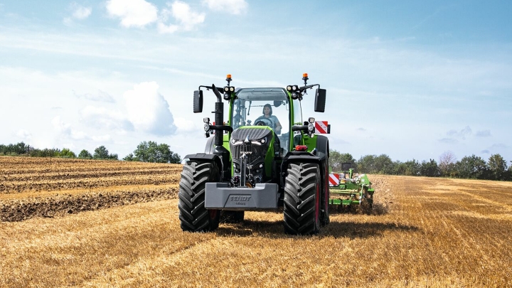 Fendt 700 Vario Gen 7 põllul tööl. Taustal on puud ja sinine taevas koos valgete pilvedega.