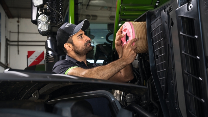 Un trabajador de atención al cliente sustituye un filtro de aire en un tractor Fendt