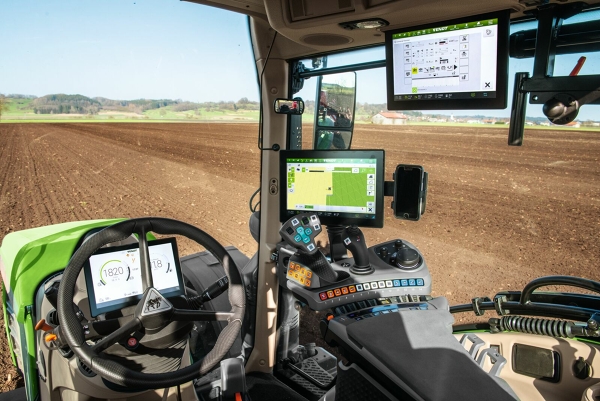 Primer plano de la cabina del Fendt 700 Vario Gen6 con vista de los tres terminales delanteros, detrás del volante y a la derecha, en el reposabrazos y en el forro del techo.