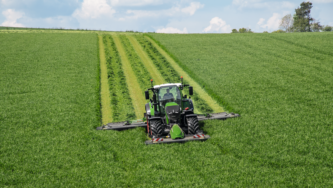 Un agricultor siega un prado con una segadora frontal y trasera Fendt Slicer.