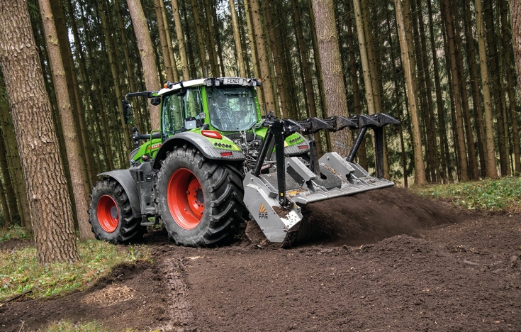 Un Fendt 700 Vario Gen7 con una fresadora en la parte trasera trabaja en un bosque de coníferas.