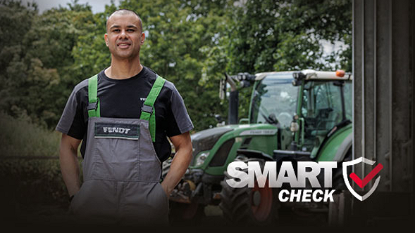 Un empleado del servicio técnico de Fendt mira amistosamente a la cámara y detrás de él se encuentra un tractor Fendt totalmente probado tras el SMART Check