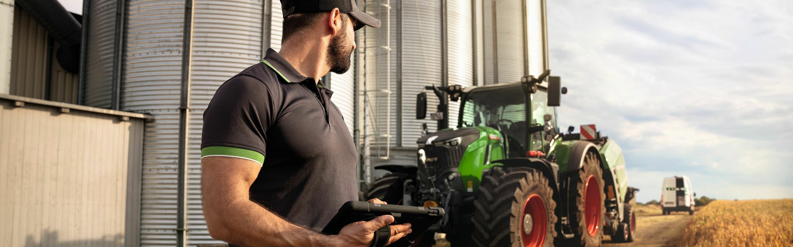 Fendtin huoltoteknikko katselee Fendt 700 Vario Gen6 -traktoria pellon reunassa.