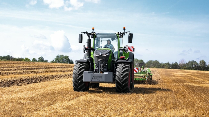 Fendt 700 Vario Gen 7 työssä pellolla. Taustalla on puita ja sininen taivas valkoisine pilvineen.