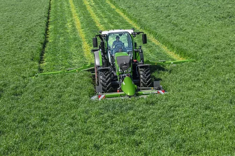 Un tracteur Fendt avec des faucheuses coupe l'herbe