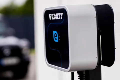 Une station de recharge électrique avec le logo Fendt installée à demeure sur un mur.