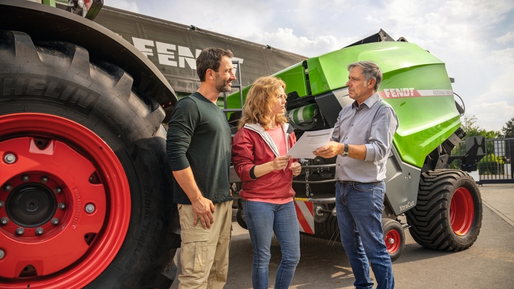 Un concessionnaire Fendt sur son site avec un couple d’agriculteurs en discussion sur la vente