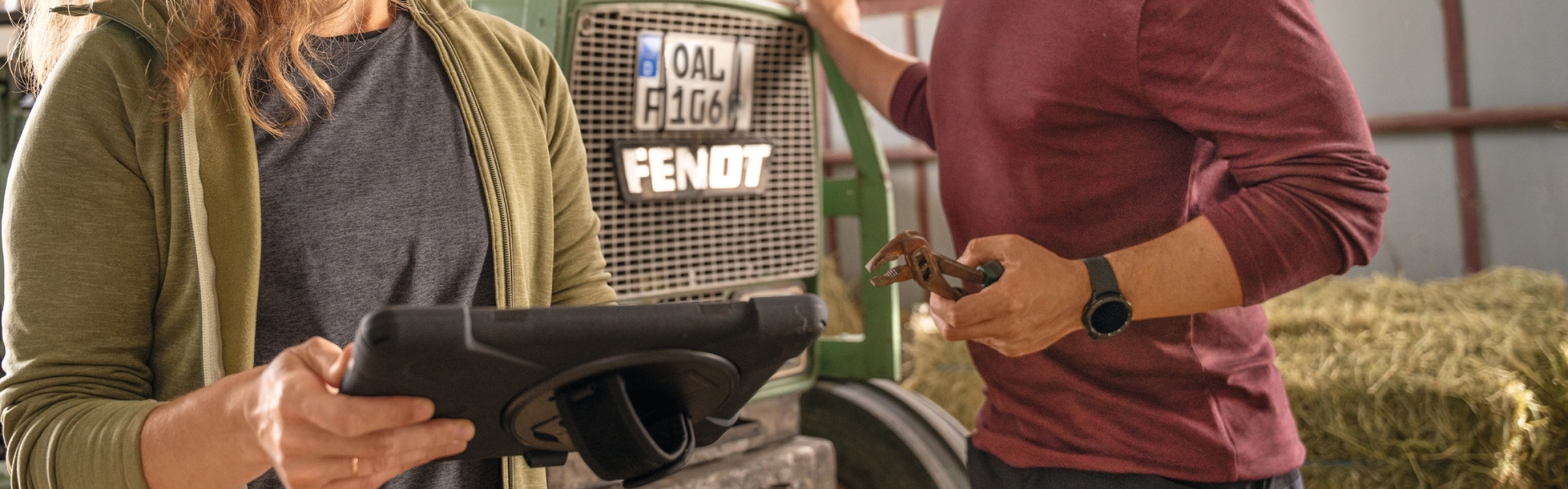 Couple d’agriculteurs devant leur tracteur historique Fendt