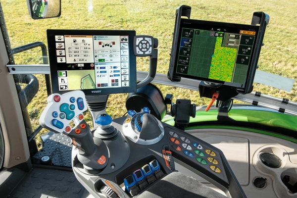 Vue de la cabine du tracteur avec accoudoir multifonction, joystick et plusieurs écrans pour l’utilisation de FendtONE