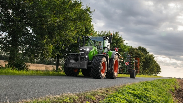 Un Fendt 728 Vario Gen7 roule sur une route de campagne avec un outil porté