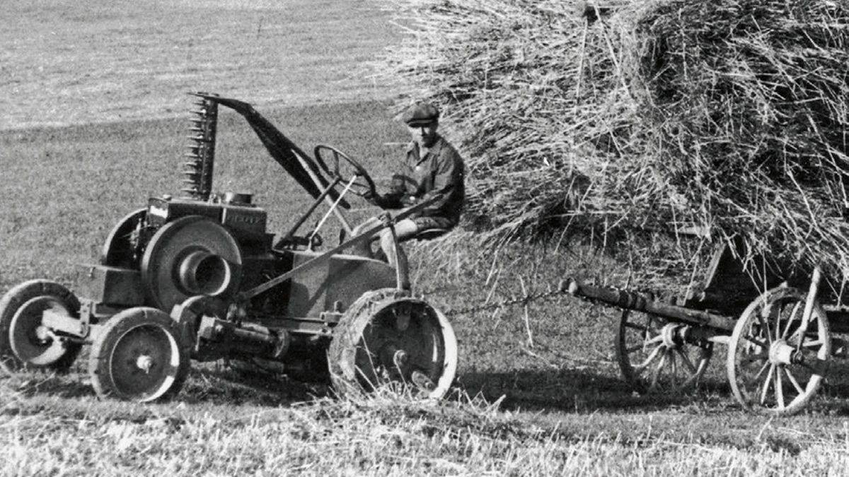 Fekete-fehér fotó egy gazdáról, aki egy régi Fendt "Dieselross"-t vezet egy réten.