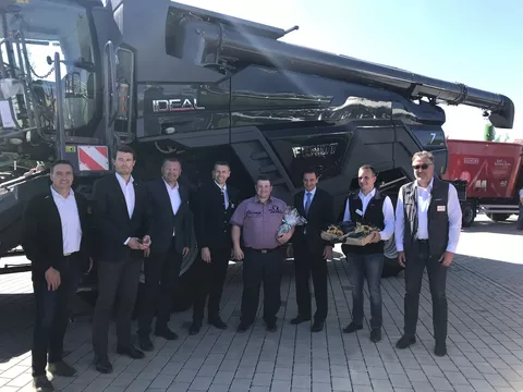 Eight men stand in front of the Fendt Ideal