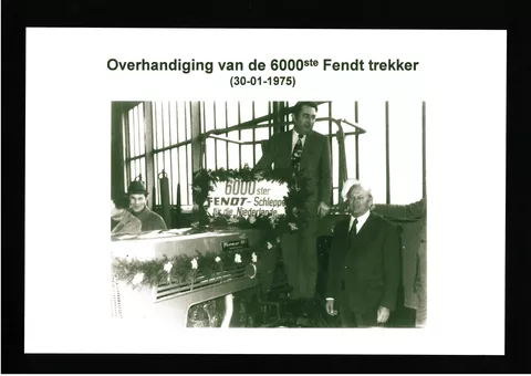 Historical black and white photo from 1975, showing 3 men around a decorated Fendt farmer with a sign ’6,000th Fendt tractor for the Netherlands’