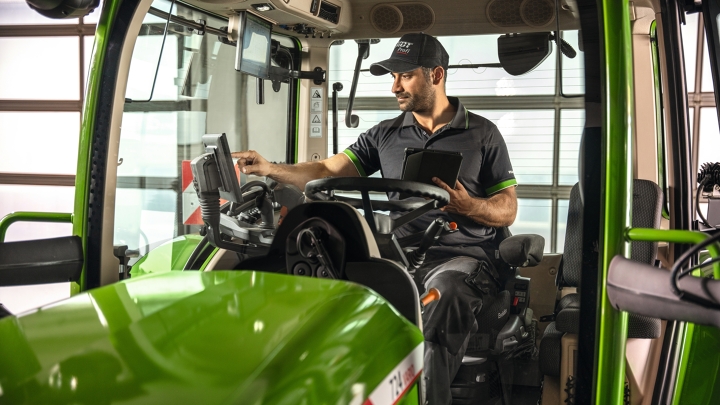 A Fendt Service employee in the Fendt tractor cab in the workshop