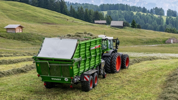 A team consisting of the typical green painted Fendt tractor and Fendt Tigo forage wagon in alpine use