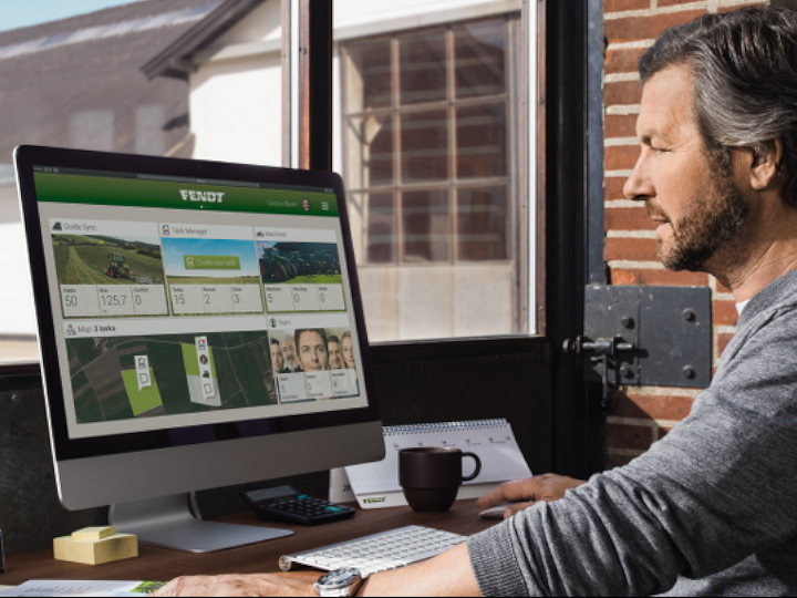 Dark-haired, middle-aged man sitting at a desk in front of a screen and watching the Fendt Task Doc