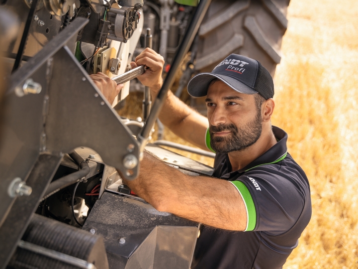 A Fendt service technician working on the harvester directly in the field