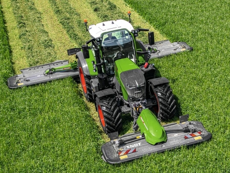 A farmer drives a Fendt 700 Vario and mows the meadow with a Fendt Slicer rear and front attachment.