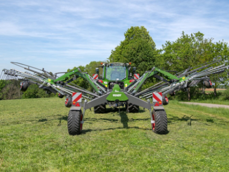 A tractor is standing on a meadow with a Fendt Former rake.