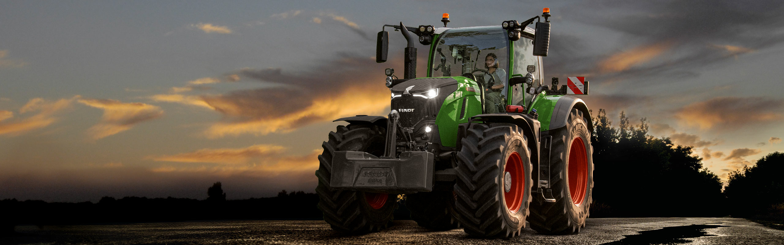 A Fendt 700 Vario Gen7 on the road in front of a dramatic sunset sky