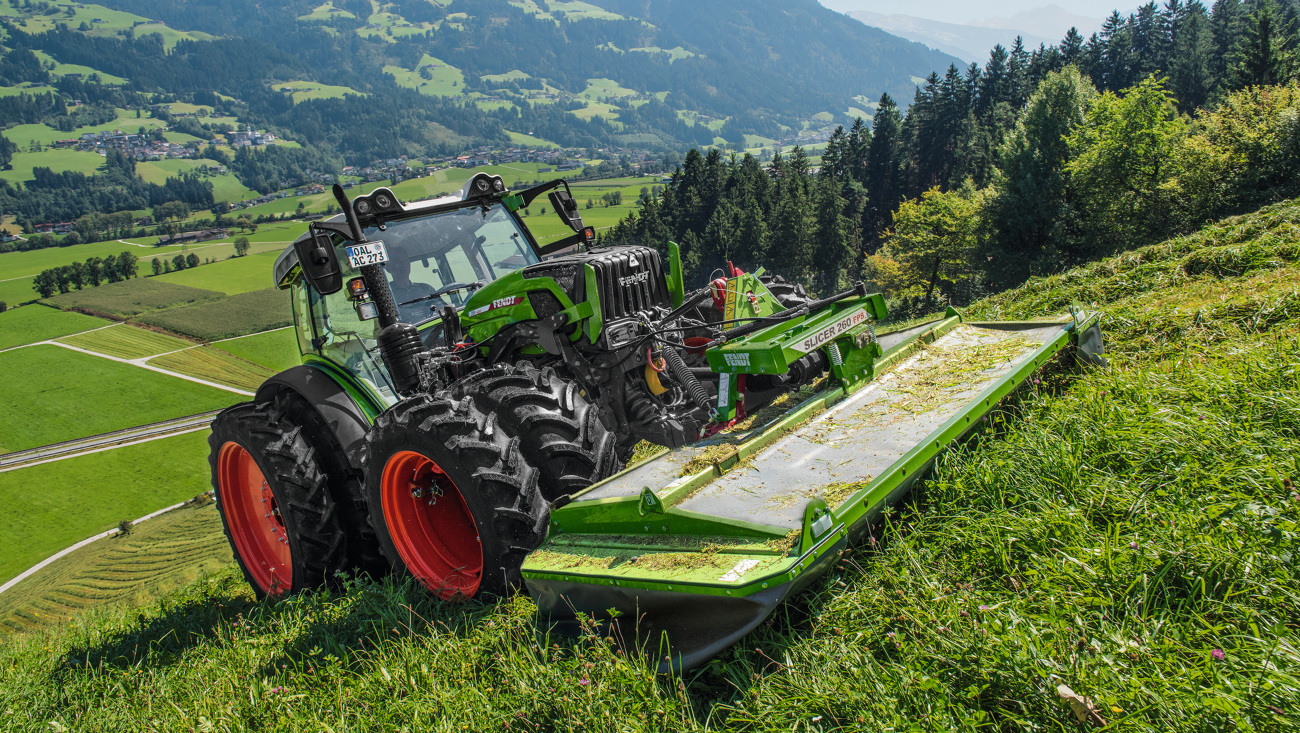 A farmer mows a slope with a Fendt Slicer front mower.