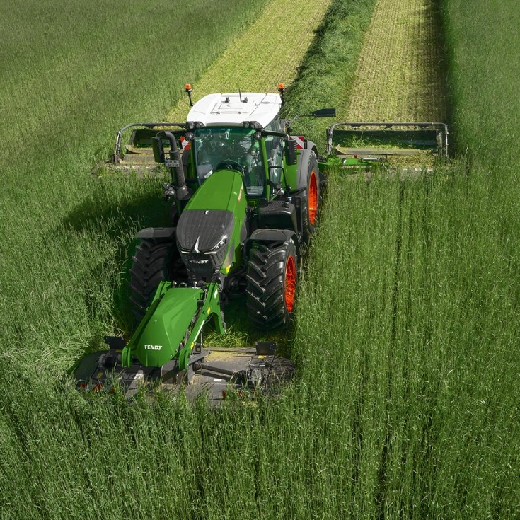 A farmer mows tall grass with a Fendt Slicer FQ mower.