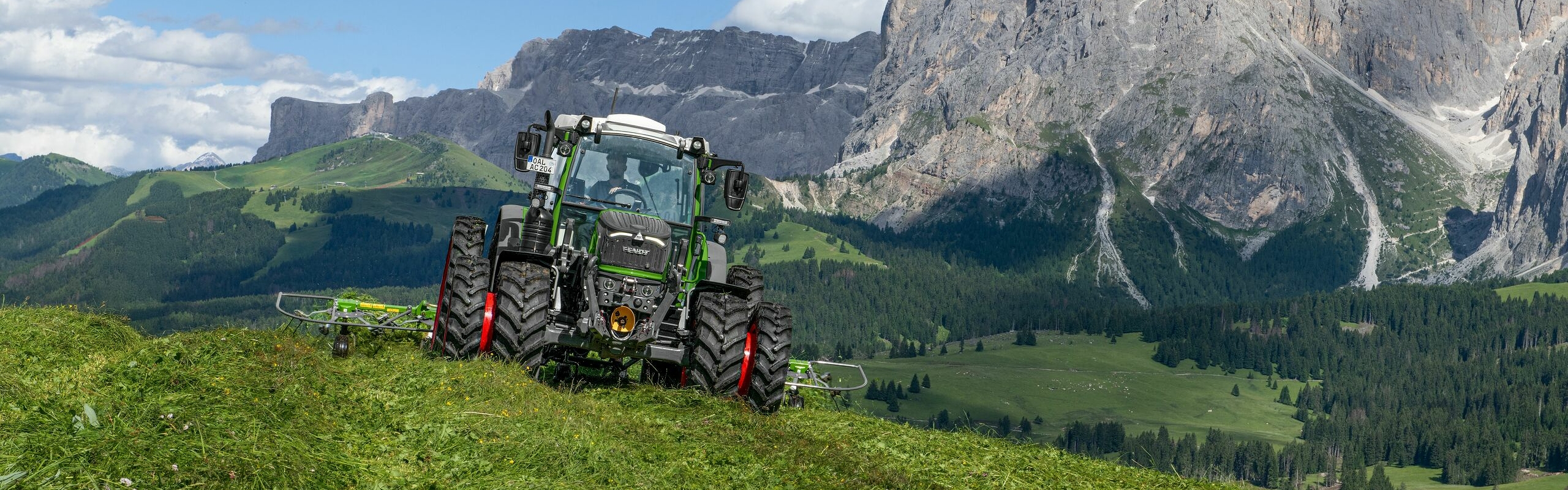 A green-painted Fendt 200 Vario in alpine terrain harvesting green forage