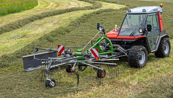 Green Fendt Former at work in a meadow, the swath marks left behind can already be seen in the background.