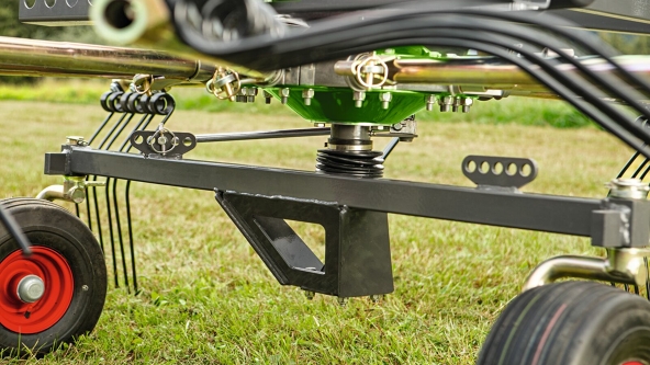 Close-up of the cam track adjustment of the Fendt Former Alpine. In the background is a green meadow.