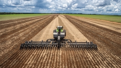 Un agricoltore procede con la seminatrice di precisione Fendt MOMENTUM su un campo.