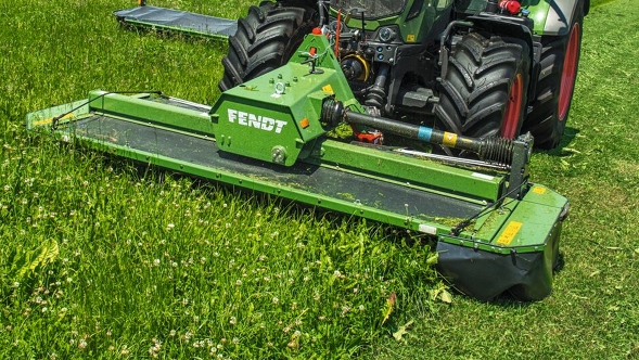 Primo piano di una Fendt Slicer 310 FPK verde che falcia erba su un prato verde.