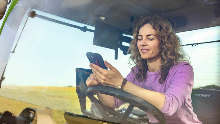 Un’agricoltrice in un trattore Fendt verde mentre utilizza la Fendt App Parts Books to go