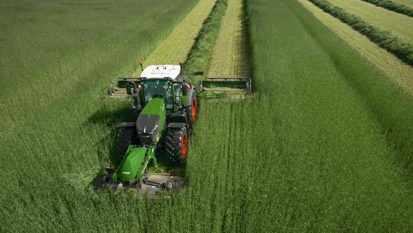 Vista dall'alto di un agricoltore che falcia un prato verde e alto con una combinazione di falciatrici Slicer FQ e Slicer PRO.