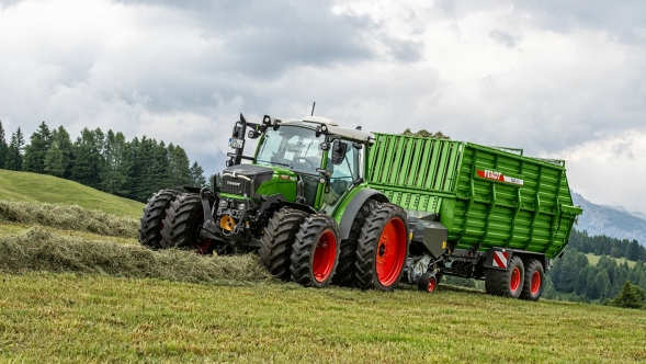 Vista di un trattore Fendt e un carro foraggero Fendt Tigo durante la raccolta di foraggio verde in ambiente alpino