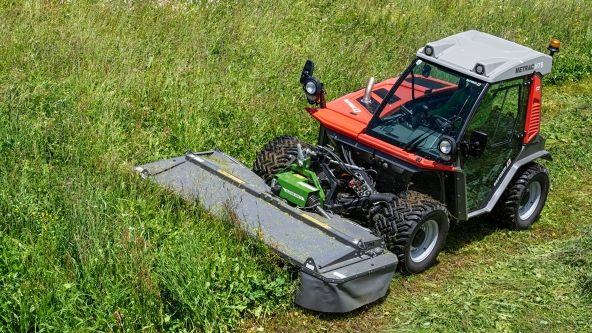 Una Fendt Slicer gamma Alpina verde falcia un prato verde e lascia la traccia di erba appena tagliata.