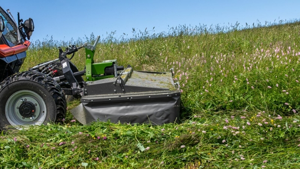 Primo piano di una Fendt Slicer gamma Alpina verde che falcia erba su un prato verde