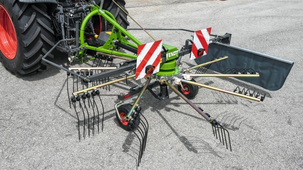 Primo piano del Fendt Former 351 DS verde su un fondo grigio.  In alto a sinistra nell’immagine si vedono gli pneumatici neri del trattore con i cerchi rossi.