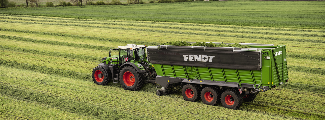 Fendt 900 Vario ar Fendt Tigo XR pašiekrāvējpiekabi, uzņemot siena vālus pļavā