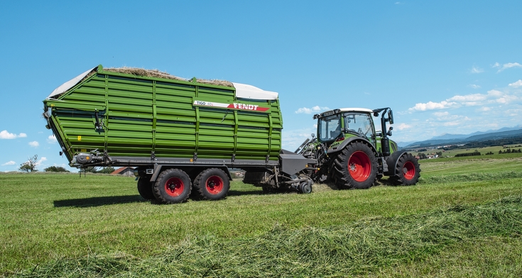 Fendt Vario traktors ar Fendt Tigo lopbarības piekabi pļavā