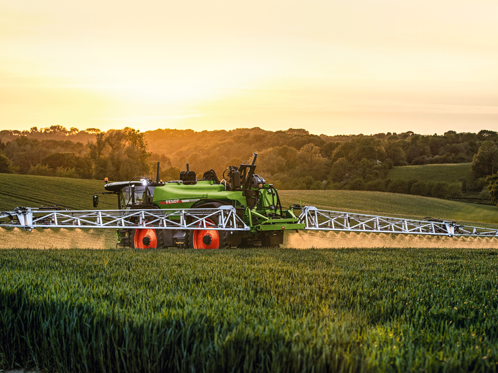 Fendt Rogator 600 pašgājējs augu aizsardzības smidzinātājs uz labības lauka saulrieta laikā.