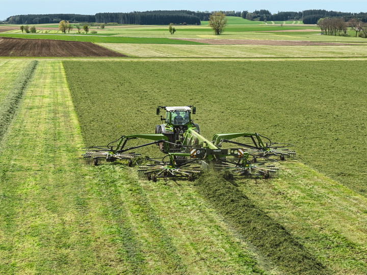 Fendt 500 Vario ar Fendt Former 4 rotoru vālotāju uz lauka veido siena vālu.