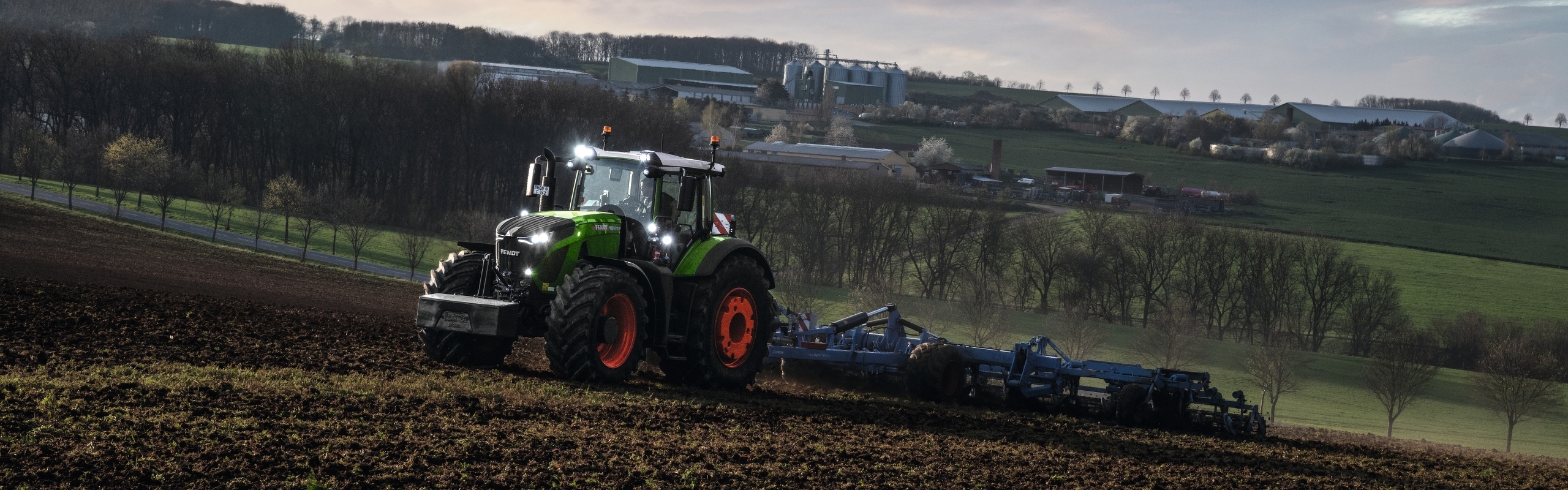 Fendt 900 Vario uz dēļa, ar sējmašīnas kombināciju un simboliem.