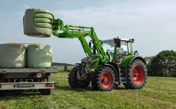 Fendt 600 Vario ar frontālo iekrāvēju paceļ apaļās ķīpas uz piekabes