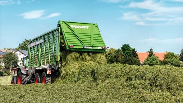 Fendt traktors brauc ar Fendt Tigo savācējpiekabi uz lauka