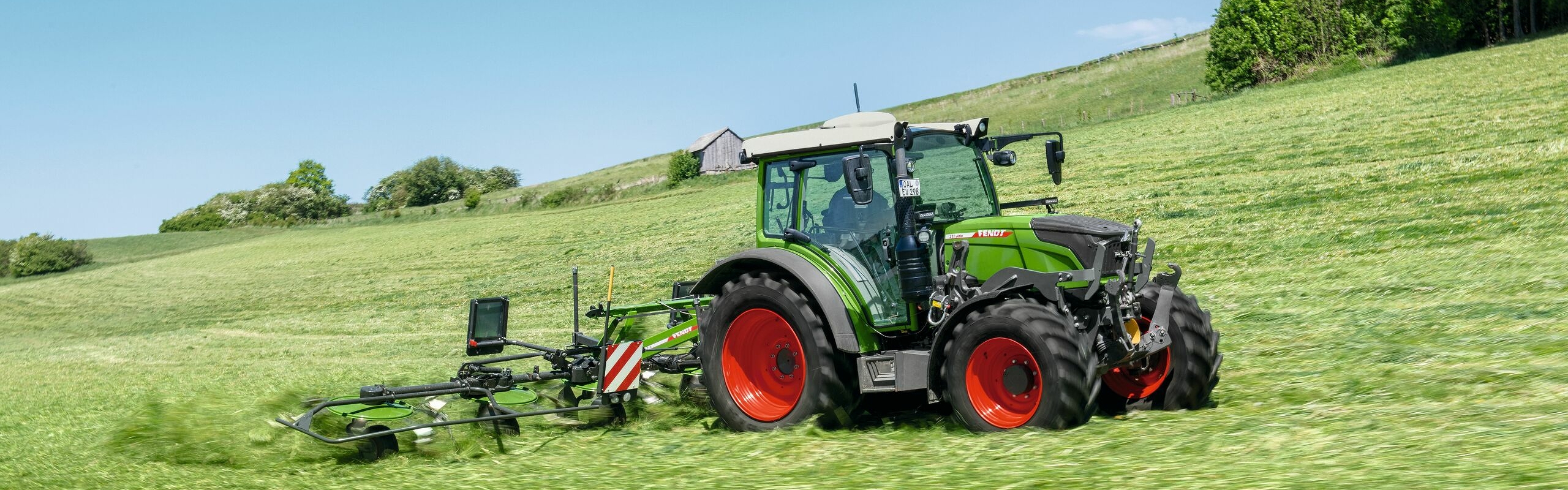 Fendt 200 Vario ar Fendt Twister pļavā darba laikā uz nogāzes