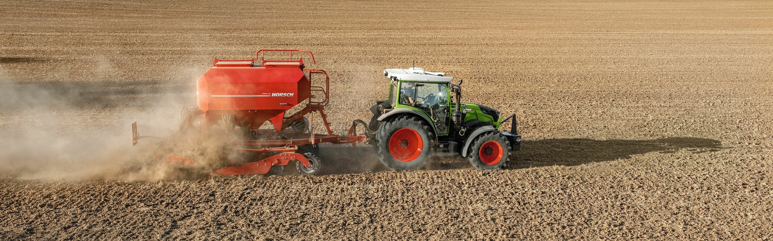 zaļš Fendt 200 Vario ar sarkanu Horsch sējmašīnu uz lauka