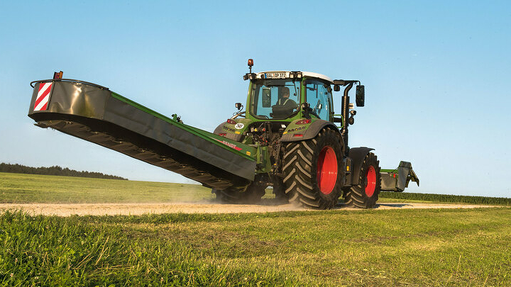 Fendt Vario traktors ar Fendt Slicer aizmugurē uzstādāmu pļaujmašīnu transportēšanas pozīcijā