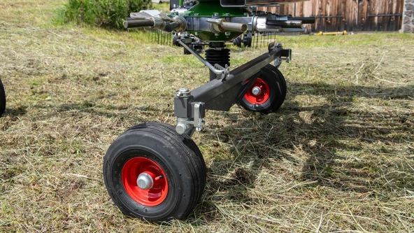 Nærbilde av de to hjulene på Fendt Alpine en-rotors samlerive på en eng.