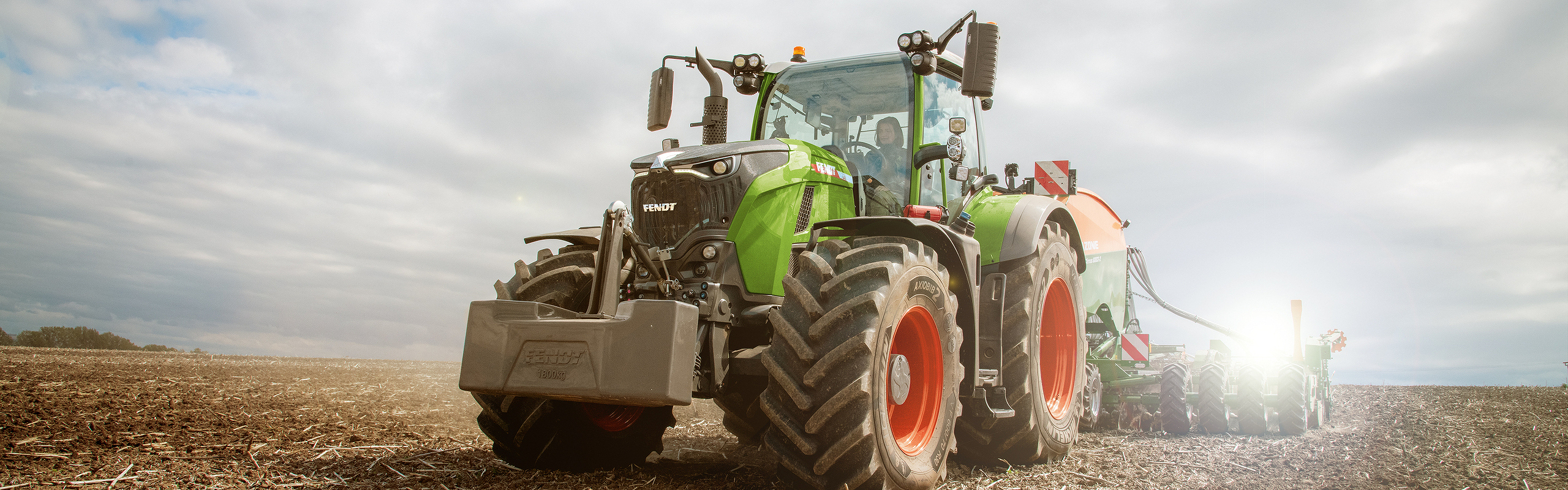 Fendt 700 Vario Gen7 jedzie po polu i wzbija tumany pyłu.